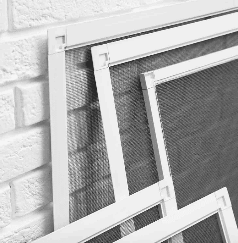 Drei Fensterschirme mit weißem Rahmen sind an eine weiße Backsteinwand gelehnt und überlappen sich. Die Schirme sind aus Mesh und das Bild ist in Schwarz-Weiß gehalten.